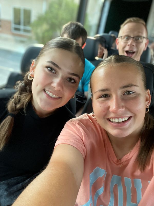 Two young ladies pose for a selfie on a bus.